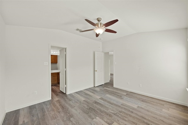 unfurnished bedroom featuring ensuite bath, vaulted ceiling, ceiling fan, and light wood-type flooring