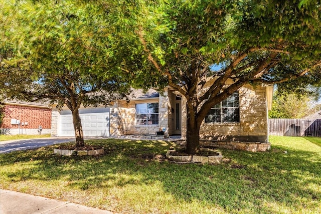 view of property hidden behind natural elements featuring a front yard and a garage