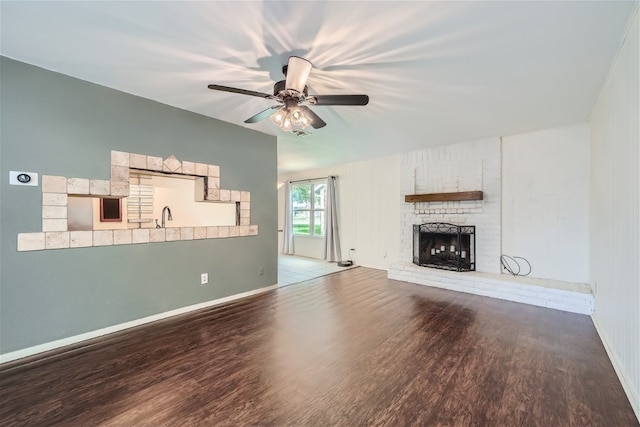 unfurnished living room with a fireplace, ceiling fan, hardwood / wood-style flooring, and sink