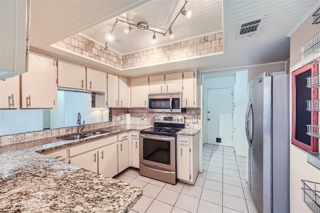 kitchen with sink, light tile patterned floors, appliances with stainless steel finishes, backsplash, and light stone countertops