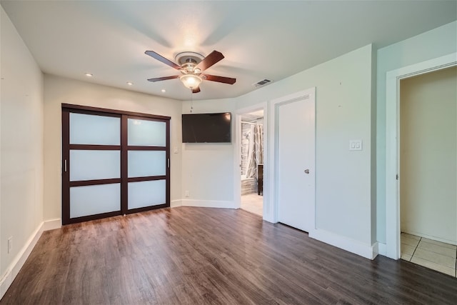 unfurnished bedroom featuring dark hardwood / wood-style flooring, a closet, a spacious closet, and ceiling fan