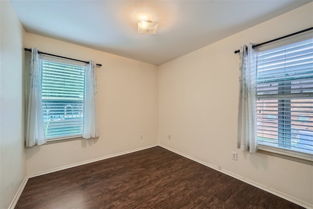 spare room with a wealth of natural light and dark wood-type flooring