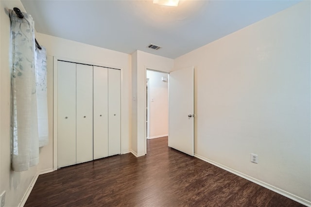 unfurnished bedroom with a closet and dark hardwood / wood-style flooring