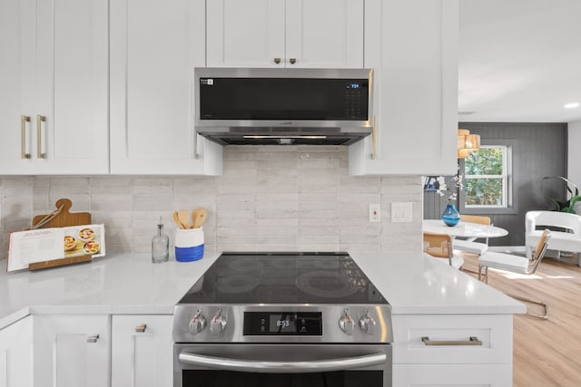 kitchen with white cabinets, appliances with stainless steel finishes, decorative backsplash, and light stone counters