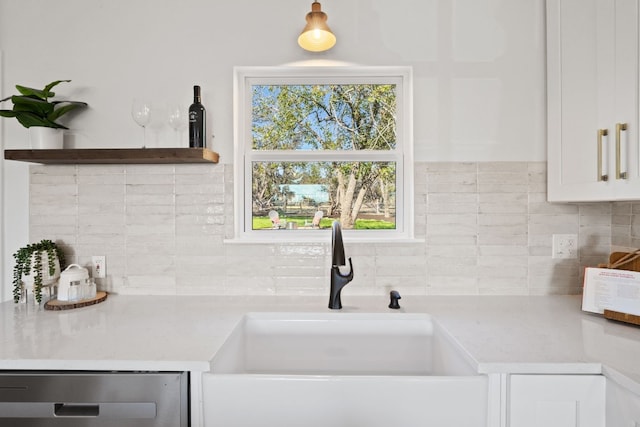 room details featuring decorative backsplash, white cabinetry, and sink