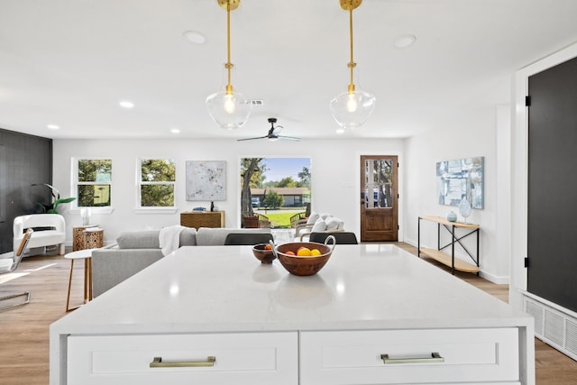 kitchen with white cabinetry, light hardwood / wood-style floors, and decorative light fixtures