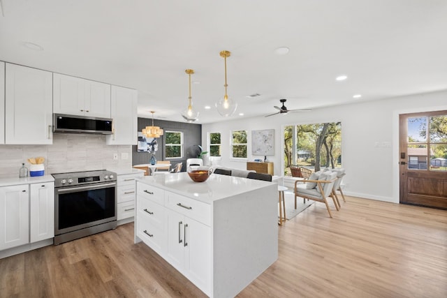 kitchen with light wood-type flooring, stainless steel appliances, white cabinetry, and hanging light fixtures