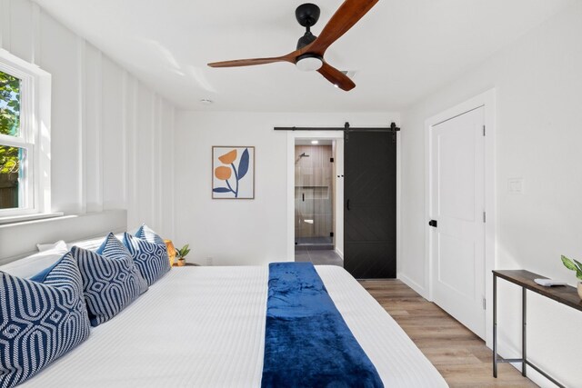 8000 Williamson Creek Dr, Austin, TX 78736 - bedroom with a barn door, light wood finished floors, connected bathroom, and a ceiling fan