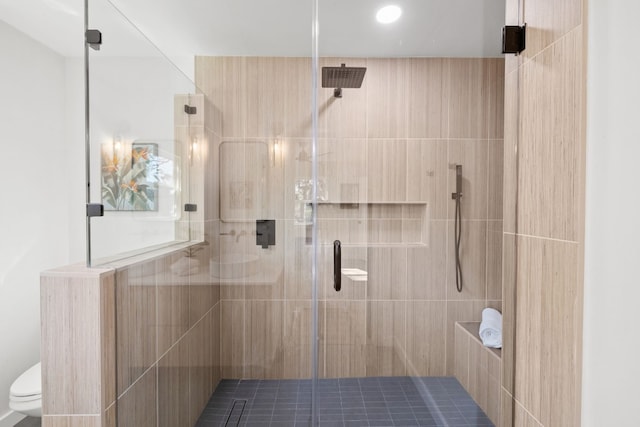 bathroom featuring a shower with door and toilet