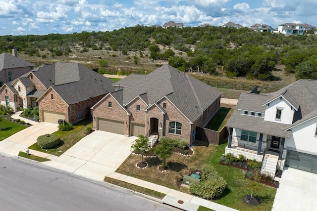 view of front facade featuring brick siding, a residential view, driveway, and roof with shingles