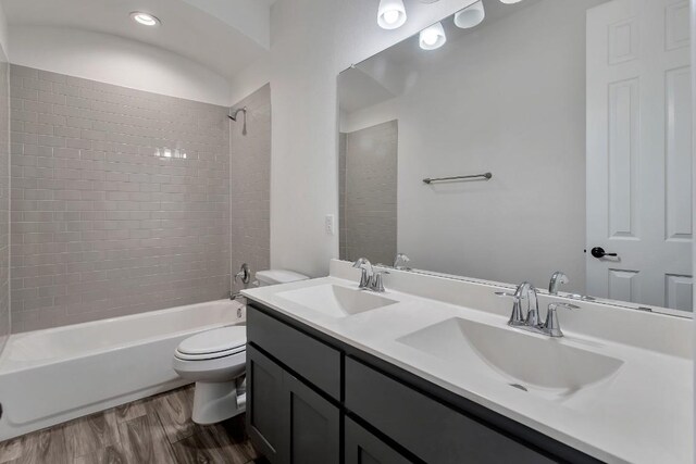 full bathroom featuring tiled shower / bath, toilet, hardwood / wood-style flooring, and vanity