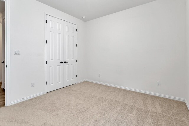 unfurnished bedroom with light carpet and a closet