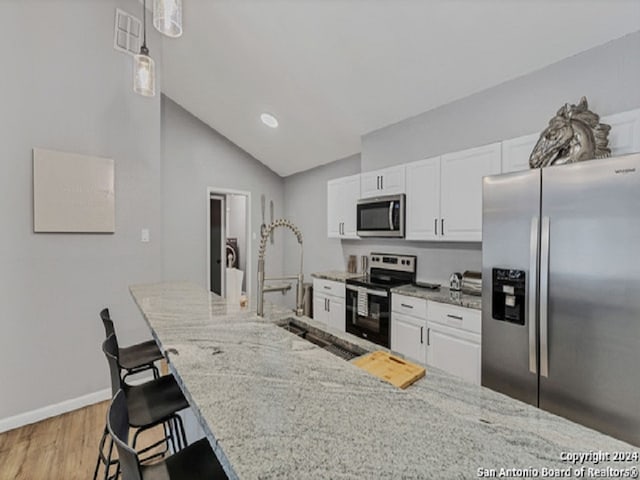 kitchen with white cabinetry, a kitchen bar, hanging light fixtures, lofted ceiling, and stainless steel appliances