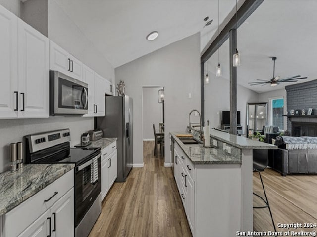 kitchen with a kitchen bar, appliances with stainless steel finishes, a fireplace, pendant lighting, and white cabinets