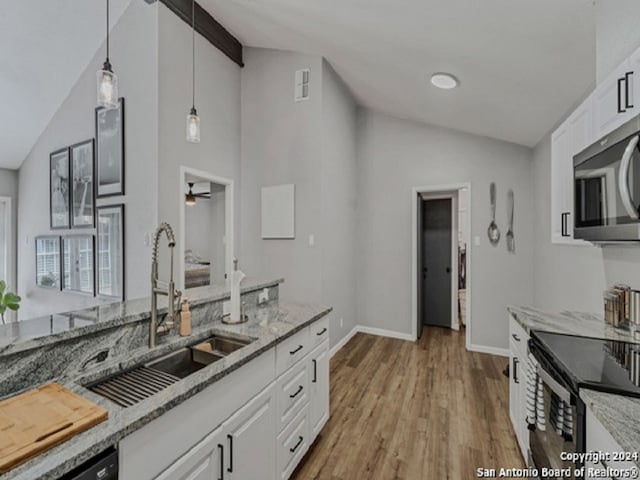 kitchen with black appliances, white cabinetry, sink, and lofted ceiling