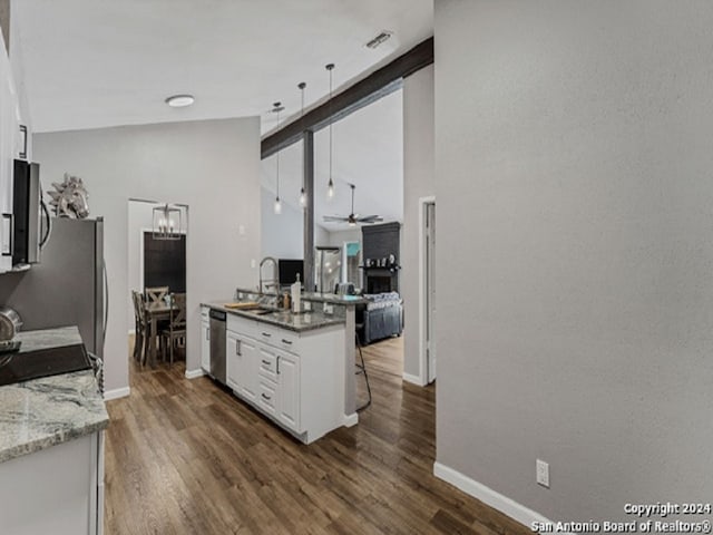 kitchen with white cabinetry, dark wood-type flooring, a breakfast bar area, stainless steel dishwasher, and ceiling fan