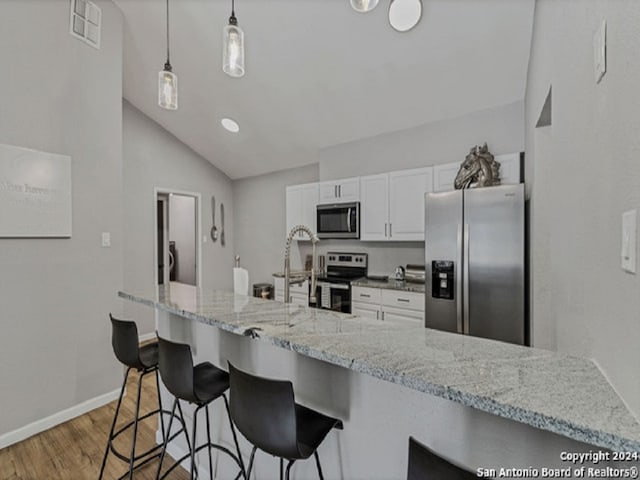 kitchen with a kitchen breakfast bar, stainless steel appliances, vaulted ceiling, white cabinets, and dark hardwood / wood-style floors