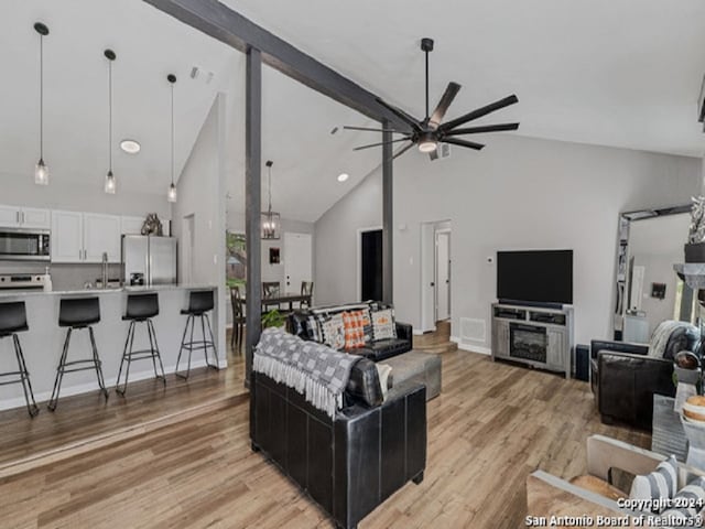 living room featuring light hardwood / wood-style flooring, sink, high vaulted ceiling, beam ceiling, and ceiling fan