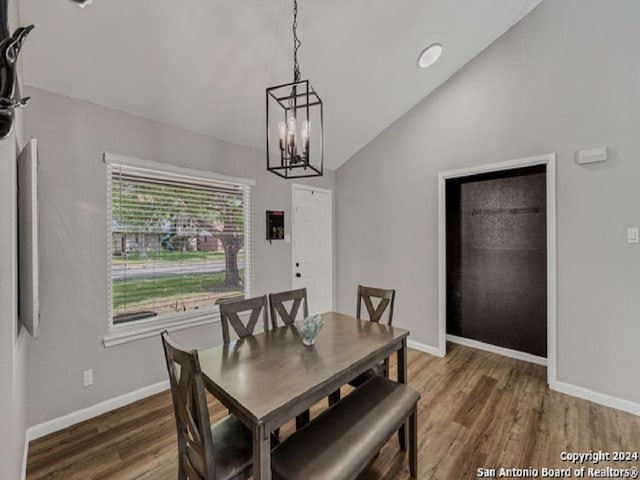 dining room with dark hardwood / wood-style floors, lofted ceiling, and an inviting chandelier