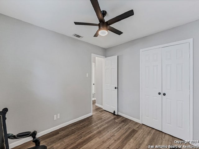 unfurnished bedroom featuring dark hardwood / wood-style flooring, a closet, and ceiling fan