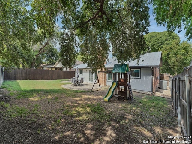 view of playground with a lawn, a patio area, and central AC unit