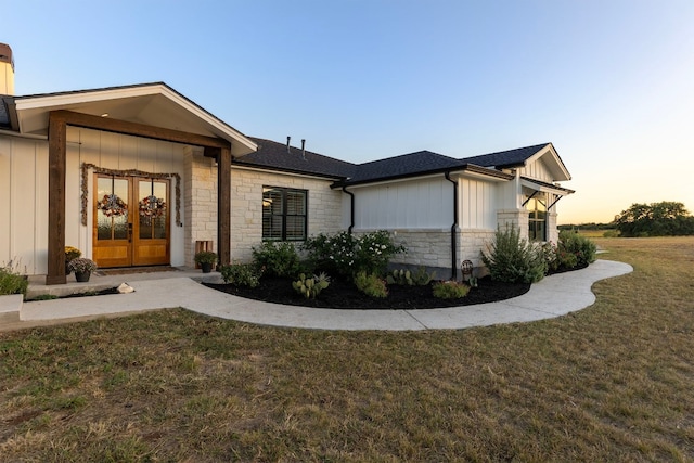 345 Judges Rd, Burnet, TX 78611 - view of front of house with stone siding, board and batten siding, a yard, french doors, and a shingled roof