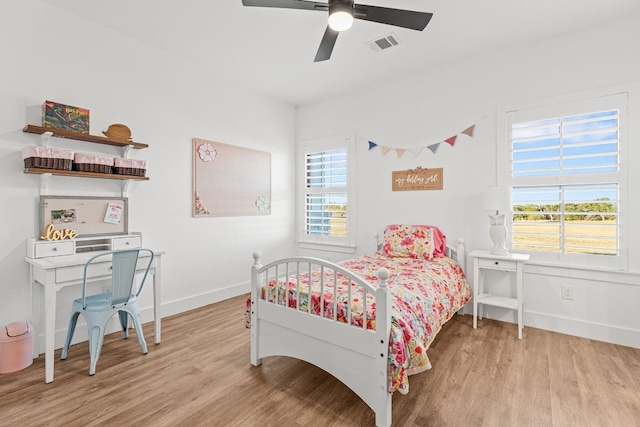 bedroom featuring light hardwood / wood-style flooring, ceiling fan, and multiple windows