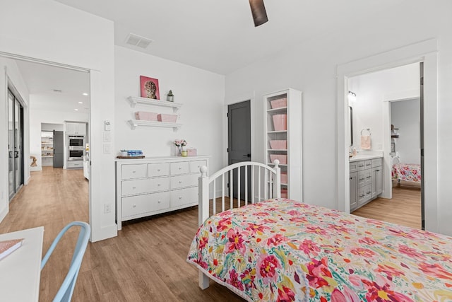 bedroom with ensuite bath, light hardwood / wood-style flooring, and ceiling fan