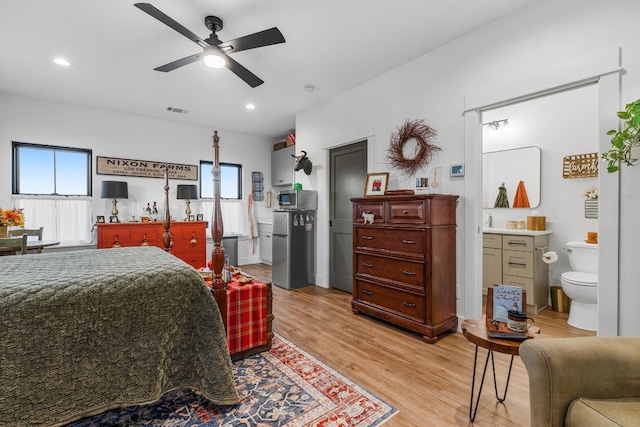 bedroom featuring stainless steel fridge, ensuite bathroom, ceiling fan, and light hardwood / wood-style floors