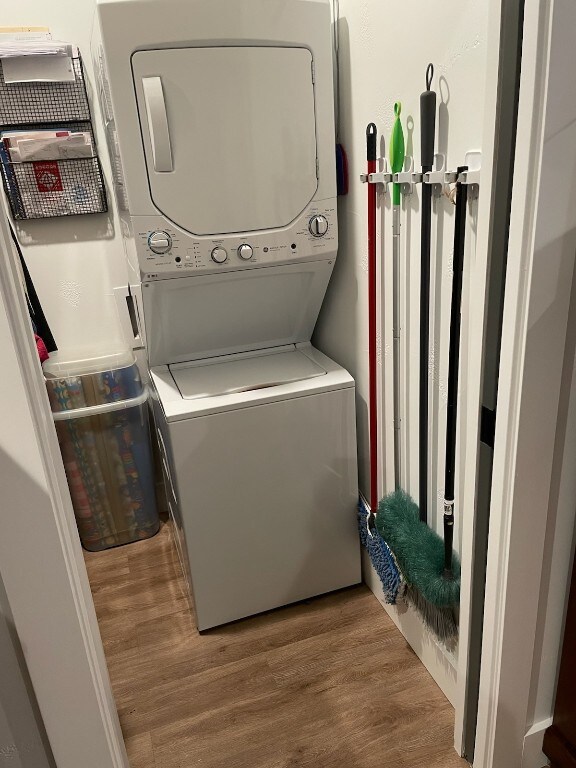 clothes washing area featuring hardwood / wood-style floors and stacked washer and dryer