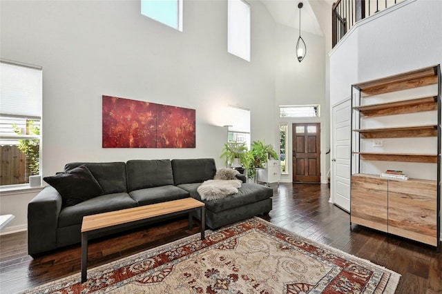 living room featuring a towering ceiling, dark wood-style floors, and baseboards