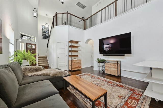 9904 Milla Cir Unit 33, Austin, TX 78748 - living room featuring a towering ceiling, arched walkways, stairway, wood finished floors, and baseboards