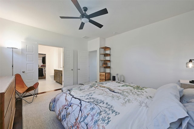 bedroom with ceiling fan, ensuite bath, and light carpet