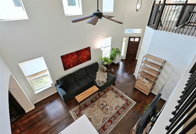 living room with stairway, a towering ceiling, and wood finished floors