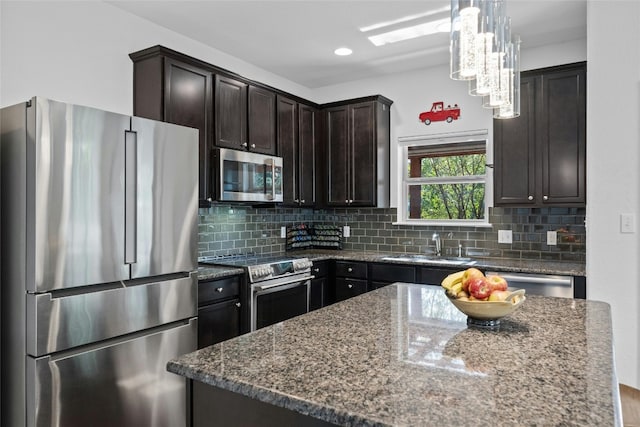 kitchen featuring stainless steel appliances, decorative light fixtures, decorative backsplash, and dark stone counters