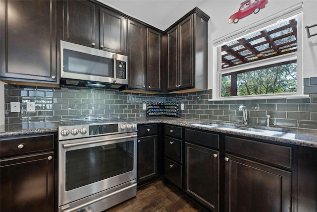 9904 Milla Cir Unit 33, Austin, TX 78748 - kitchen with stainless steel appliances, a sink, dark stone countertops, dark wood finished floors, and decorative backsplash