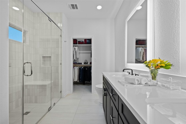 bathroom with a shower with door, vanity, tile patterned floors, and toilet