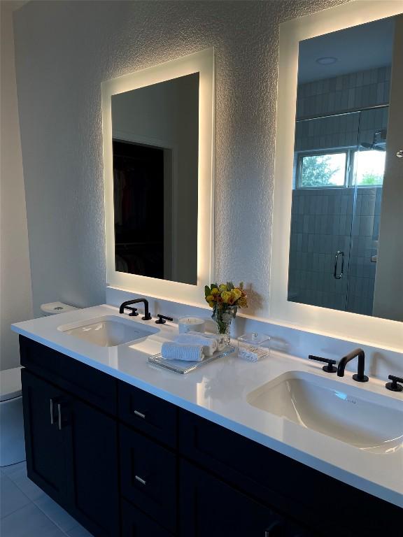 bathroom featuring tile patterned floors, vanity, toilet, and an enclosed shower