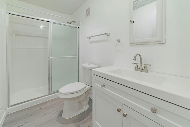 bathroom with vanity, toilet, wood-type flooring, and a shower with door