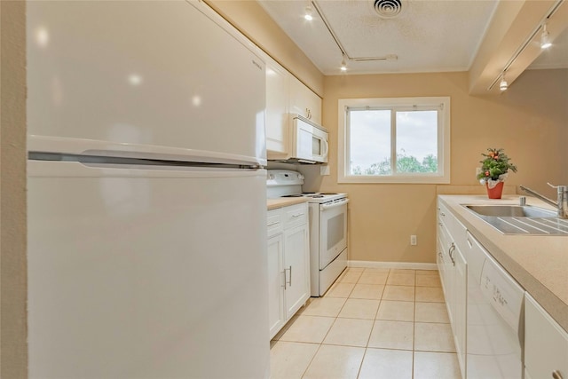 kitchen with sink, light tile patterned floors, a textured ceiling, white appliances, and white cabinets