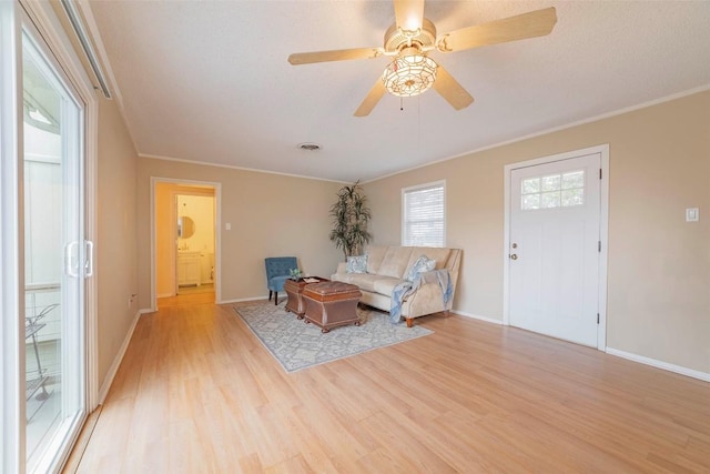 living room featuring light hardwood / wood-style flooring, ceiling fan, and ornamental molding