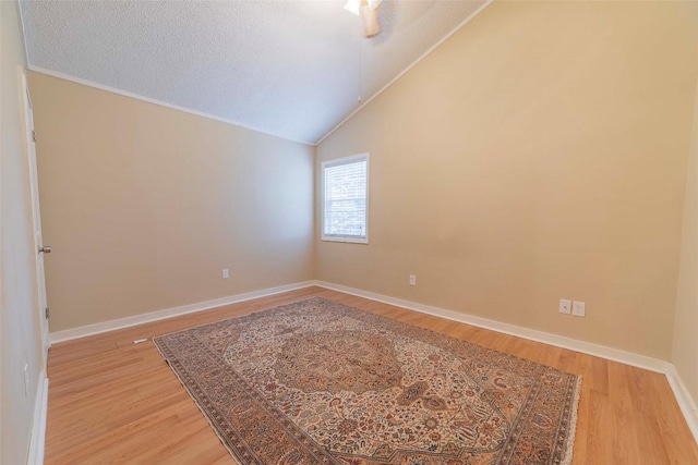 unfurnished room featuring a textured ceiling, hardwood / wood-style flooring, and vaulted ceiling