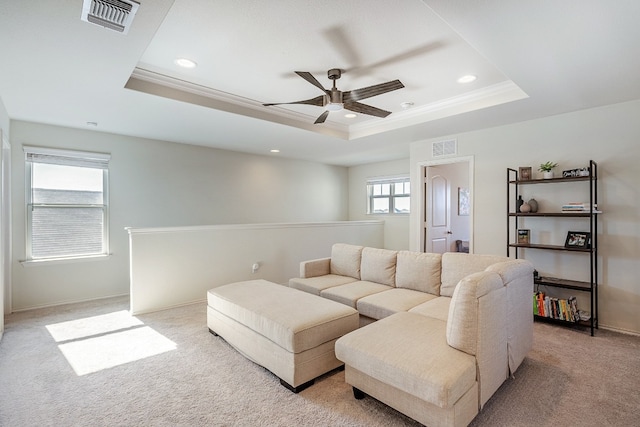 living room featuring a tray ceiling, ceiling fan, crown molding, and light colored carpet