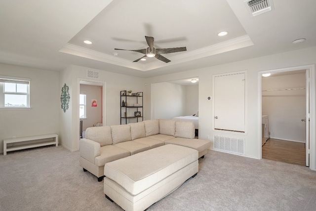 carpeted living room with a baseboard heating unit, a tray ceiling, ceiling fan, and crown molding