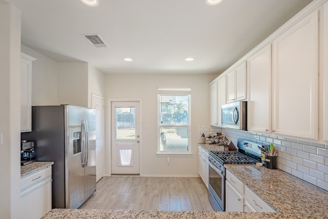 kitchen featuring white cabinetry, tasteful backsplash, light wood-type flooring, light stone countertops, and stainless steel appliances