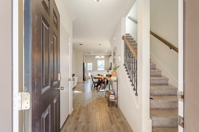 foyer entrance with light wood-type flooring and an inviting chandelier