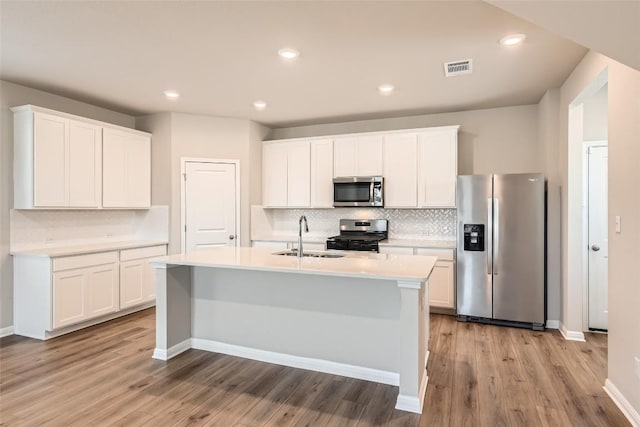 196 Lost Mine Peak Ln, Dripping Springs, TX 78620 - kitchen featuring appliances with stainless steel finishes, a sink, decorative backsplash, light countertops, and a kitchen island with sink
