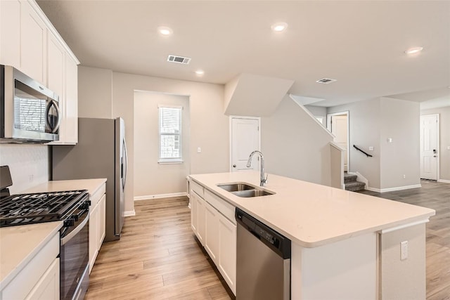 196 Lost Mine Peak Ln, Dripping Springs, TX 78620 - kitchen featuring appliances with stainless steel finishes, a sink, light wood-style flooring, white cabinetry, and recessed lighting