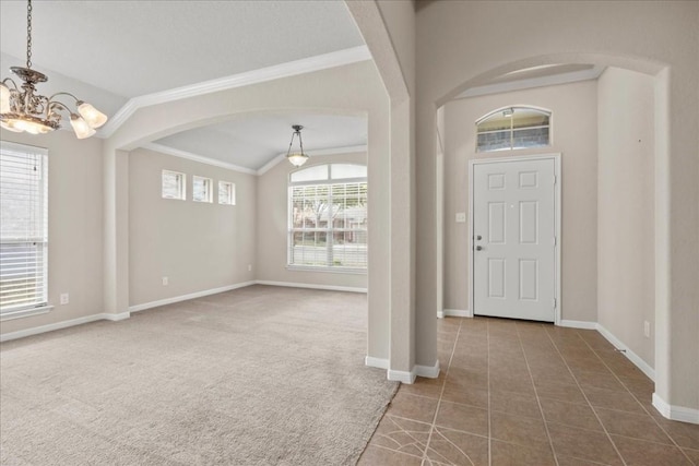 carpeted entrance foyer featuring a chandelier, lofted ceiling, and ornamental molding