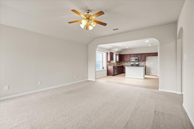 unfurnished living room featuring ceiling fan, light colored carpet, and lofted ceiling